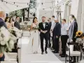 Para młoda idzie do ołtarza na ślubie cywilnym. Panna młoda w białej sukni z bukietem kwiatów, pan młody w granatowym garniturze.