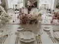 Eleganckie nakrycie stołu na wesele w stylu romantycznym. Delikatne kwiaty, złote sztućce i kryształowe kieliszki tworzą magiczną atmosferę.