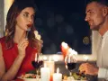 Romantyczna kolacja przy świecach. Ona, w czerwonej sukience, zmysłowo je, a on patrzy na nią z uwielbieniem. Widać oznaki flirtu dziewczyny w jej spojrzeniu.