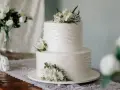 Elegancki tort weselny z białymi kwiatami, idealny na życzenia na ślub dla przyjaciół.