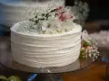Elegancki tort weselny z żywymi kwiatami, udekorowany delikatnymi białymi kwiatami i gipsówką.