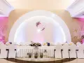 Eleganckie wesele w stylu nowoczesnym. Długi stół weselny nakryty białym obrusem, ozdobiony kwiatami i lampionami. W tle serce z imionami pary młodej.