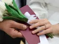 Para weselna trzyma bukiet białych tulipanów i akt małżeństwa. Zastanawiasz się, ile się daje na wesele?