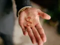 Dwie złote obrączki na dłoni mężczyzny. Kto kupuje obrączki? Ten, kto planuje ślub.