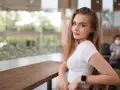 Uśmiechnięta blondynka w białej bluzce, z zegarkiem na ręku, siedzi przy stoliku. Czy to jej sekret, jak uwieść faceta?