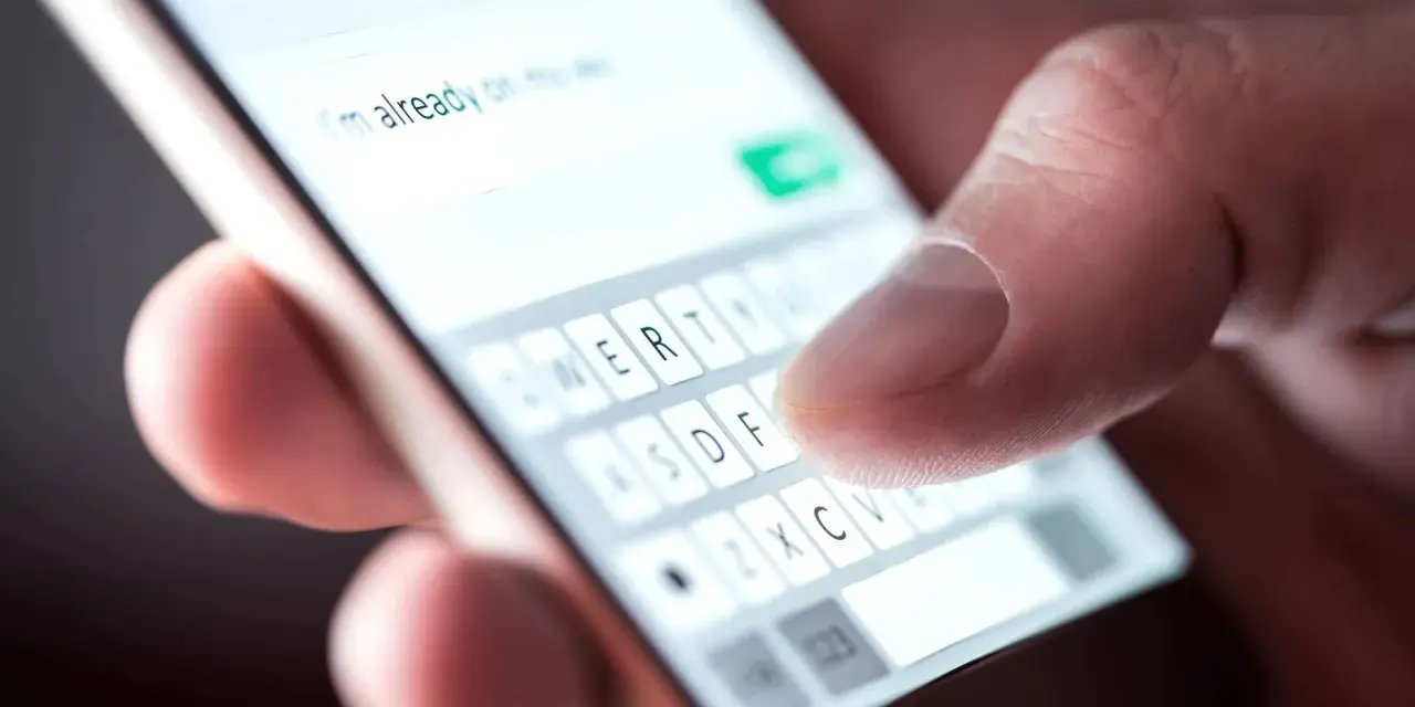 Pisanie wiadomości: "Dziękuję za zaproszenie, potwierdzam przybycie!" na ekranie telefonu.