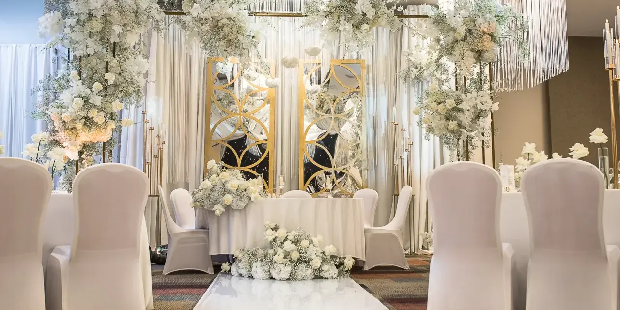 Elegancka sala weselna z białymi kwiatami i złotymi lustrami. Idealne miejsce, by zorganizować przyjęcie po ślubie cywilnym.