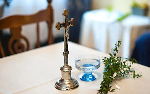 Krzyż, kropielniczka i gałązka – przygotowania do błogosławieństwa pana młodego w domu.