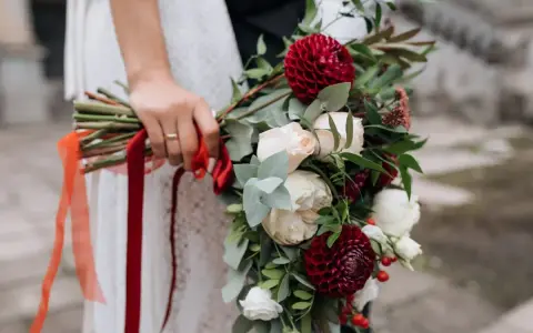 Elegancki bukiet z czerwonych i białych kwiatów, ozdobiony wstążkami, idealny jako kwiaty na ślub w prezencie.
