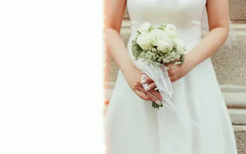 Panna młoda trzyma bukiet białych róż. Kwiaty symbolizują czystość i miłość, a ich znaczenie jest głębokie w dniu ślubu.