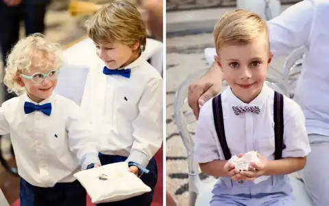Dwóch chłopców w eleganckich strojach niesie obrączki na poduszce. Jeden z nich ma okulary.