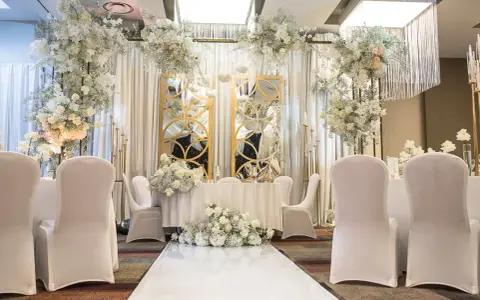 Elegancka sala weselna z białymi kwiatami i złotymi lustrami. Idealne miejsce, by zorganizować przyjęcie po ślubie cywilnym.