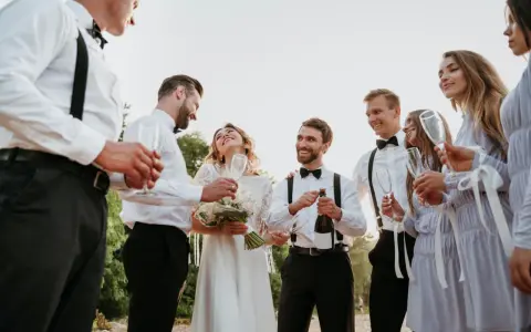 Świadek na ślubie otwiera szampana, podczas gdy panna młoda i jej drużba trzymają kieliszki.