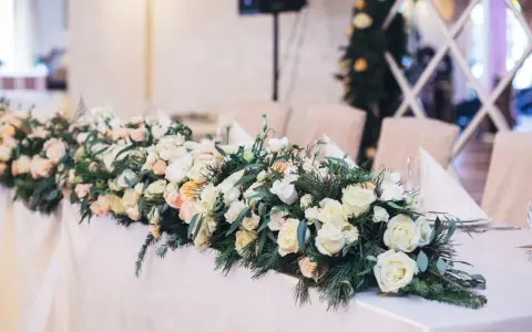 Eleganckie kwiaty na wesele zdobią stół, tworząc romantyczną atmosferę. Bukiet z róż i zieleni.