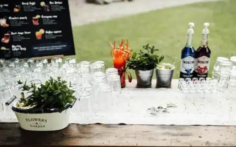 Samoobsługowy drink bar na weselu z przepisami na drinki. Szklanki, syropy Monin, świeża mięta i akcesoria barmańskie czekają na gości.