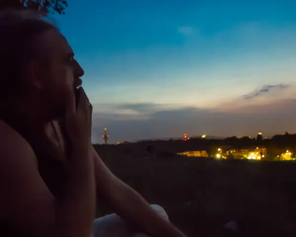 Mężczyzna zamyślony patrzy na nocne miasto. Odeszłam, ale tęsknię za tym widokiem.