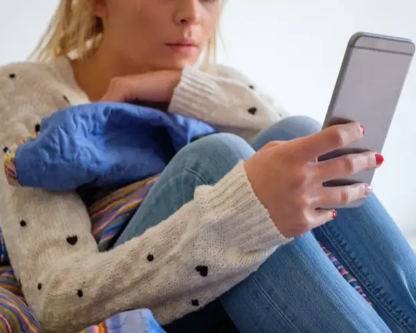Dziewczyna w swetrze z serduszkami czeka na wiadomość, czy to już ghosting powrót?