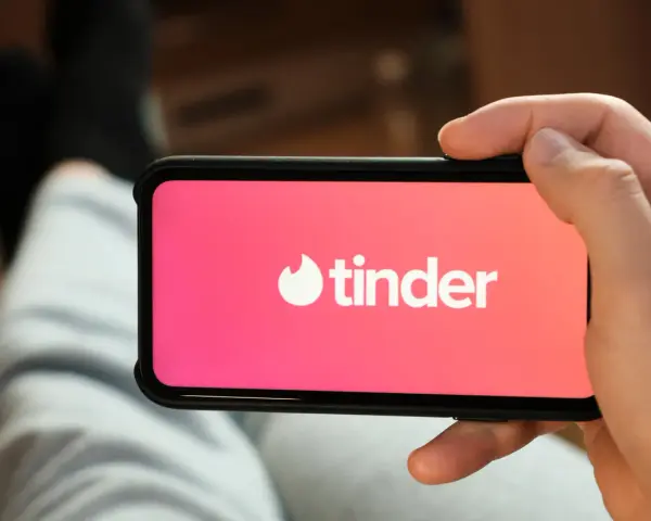 Dłoń trzyma smartfon z otwartą aplikacją do randkowania Tinder.