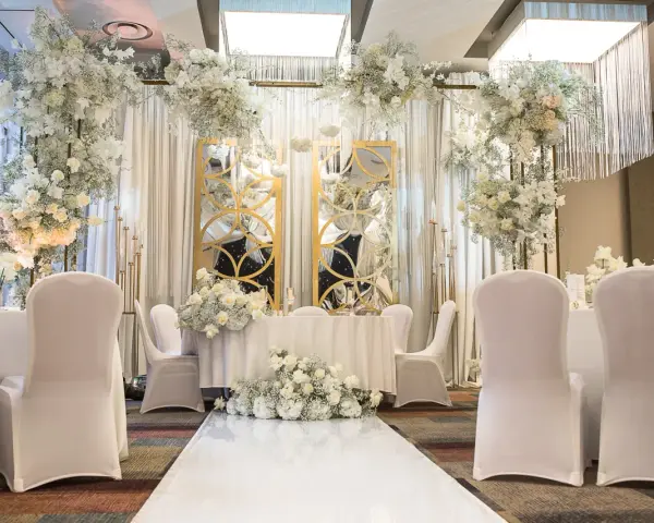 Elegancka sala weselna z białymi kwiatami i złotymi lustrami. Idealne miejsce, by zorganizować przyjęcie po ślubie cywilnym.