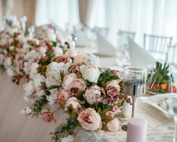 Elegancki wystrój sali weselnej z obfitymi bukietami piwonii w pastelowych kolorach, tworzącymi romantyczną atmosferę.