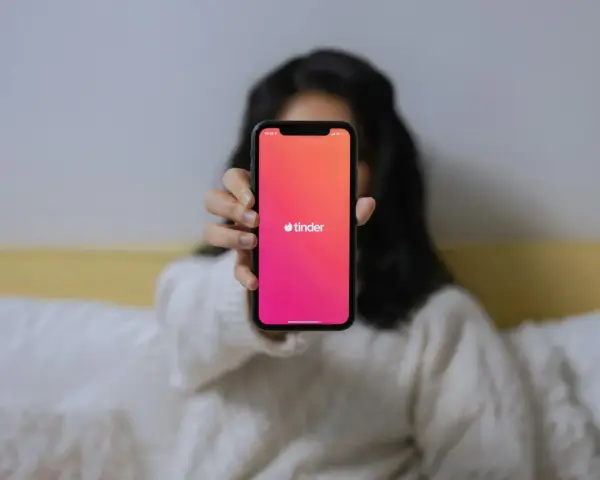 Dłoń trzyma telefon z logo Tindera. Zastanawiasz się, czemu nie mogę usunąć konta na Tinderze?