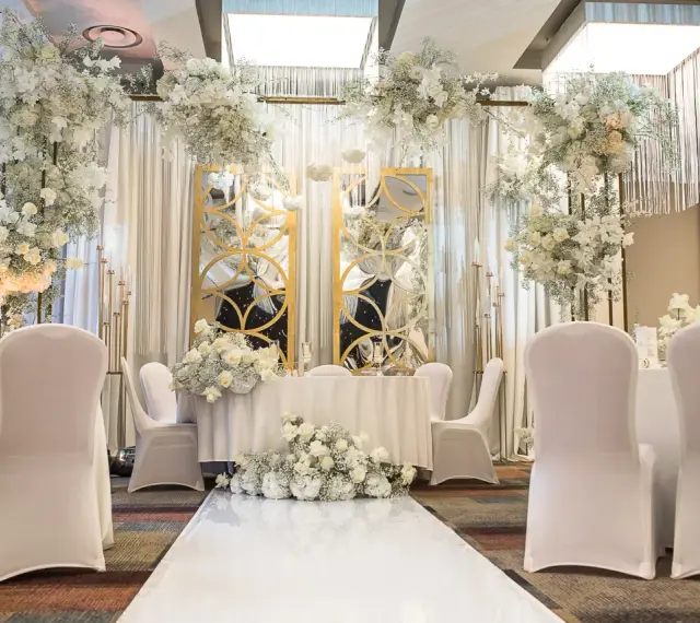 Elegancka sala weselna z białymi kwiatami i złotymi lustrami. Idealne miejsce, by zorganizować przyjęcie po ślubie cywilnym.