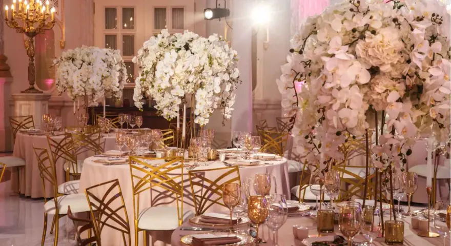 Eleganckie stoły z białymi kwiatami i złotymi krzesłami tworzą styl glamour wesele.