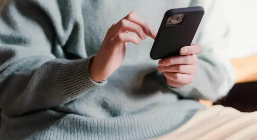 Dłonie trzymające telefon, zastanawiające się, co napisać po kłótni.
