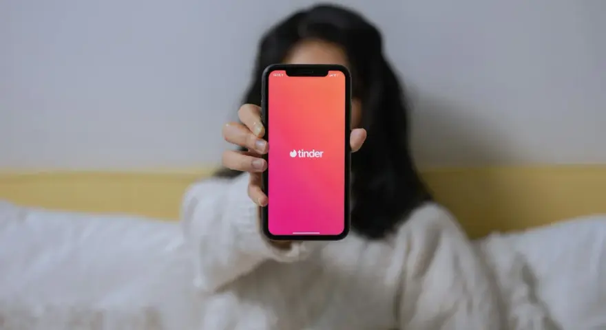 Dłoń trzyma telefon z logo Tindera. Zastanawiasz się, czemu nie mogę usunąć konta na Tinderze?