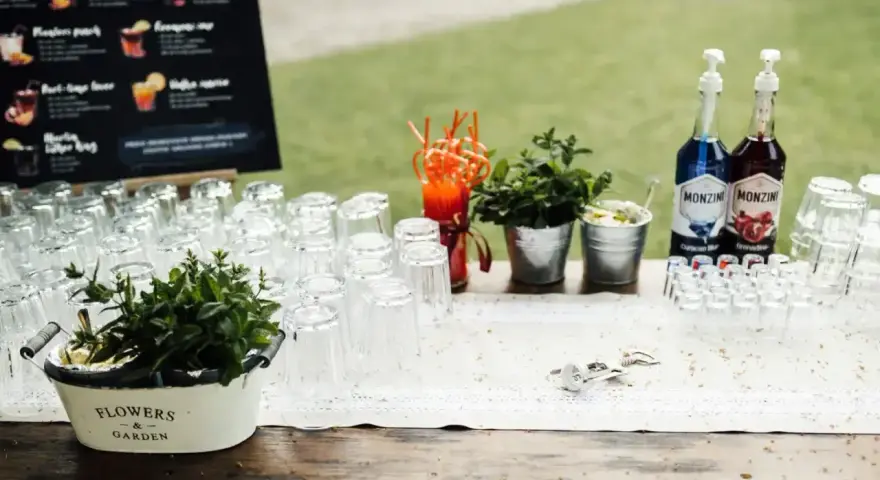 Samoobsługowy drink bar na weselu z przepisami na drinki. Szklanki, syropy Monin, świeża mięta i akcesoria barmańskie czekają na gości.