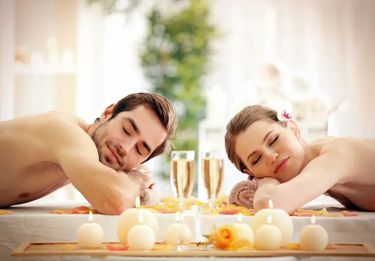 Para relaksujący, namiętny masaż dla pary. Płonące świece, płatki róż i szampan tworzą romantyczną atmosferę.