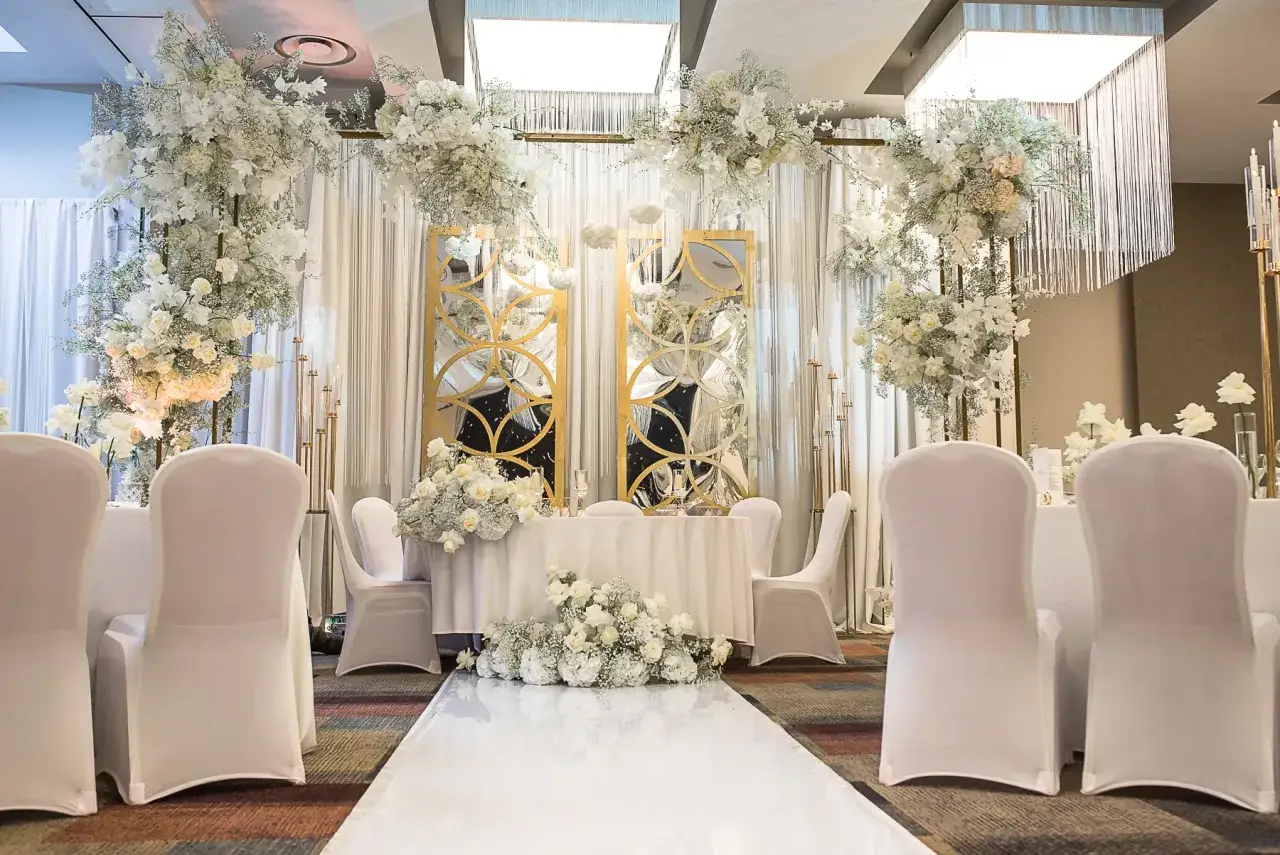 Elegancka sala weselna z białymi kwiatami i złotymi lustrami. Idealne miejsce, by zorganizować przyjęcie po ślubie cywilnym.